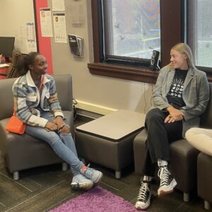 A student and teacher sitting on chairs talking
