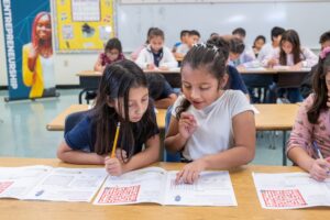 Two students working together on a workbook in a classroom