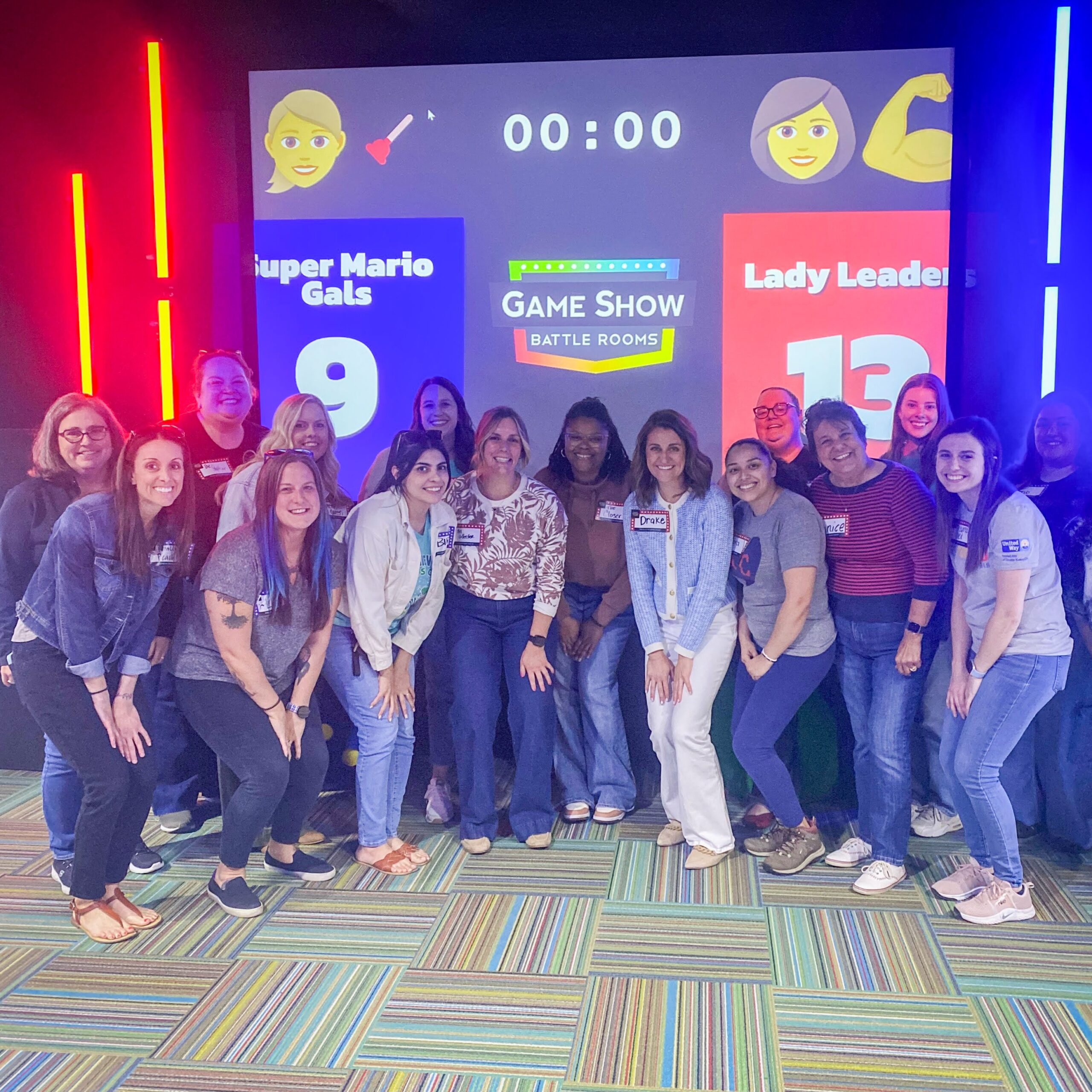 Group of smiling employees standing in front of a screen, posing for a group photo