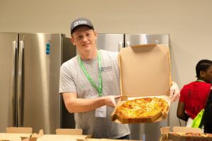 JA BizTown volunteer in the cafe holding a pizza