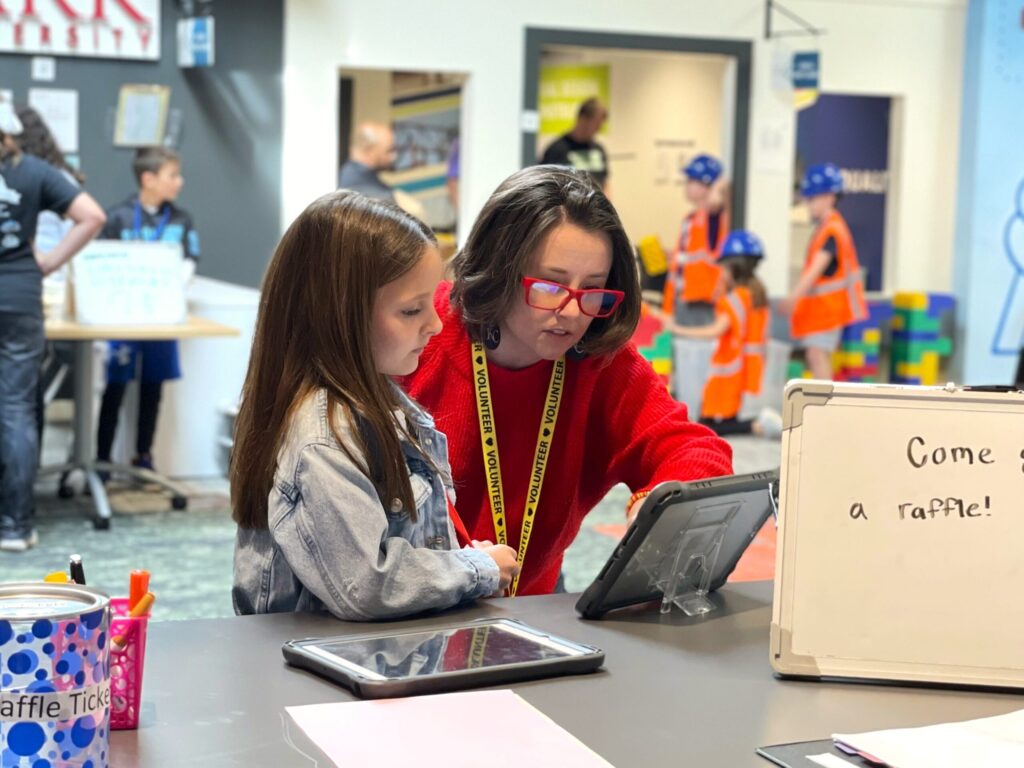 Volunteer and student looking at iPad in JA BizTown