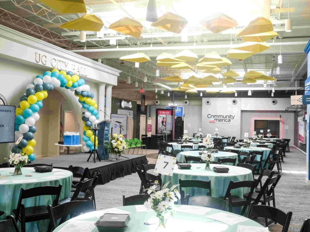 An array of tables with centerpieces and a balloon arch are set up before a Hall of Fame event