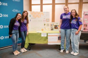 Group of students standing in front of a booth with a display