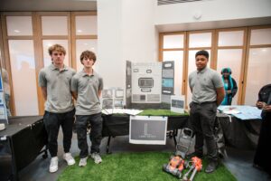 Group of students standing in front of a booth with a display