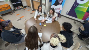 Business coaches sitting at a table, speaking with students
