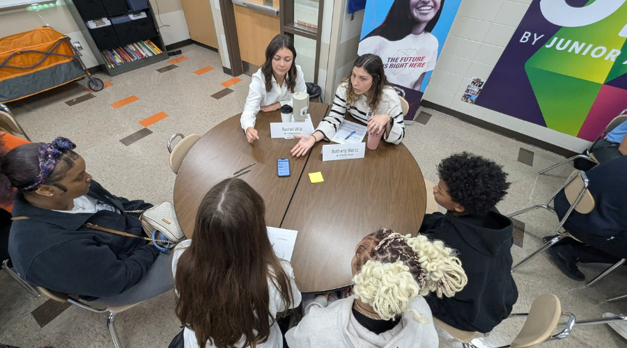 Business coaches sitting at a table, speaking with students