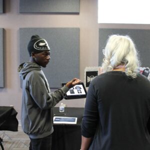 A student holding a tablet and having a conversation with someone.
